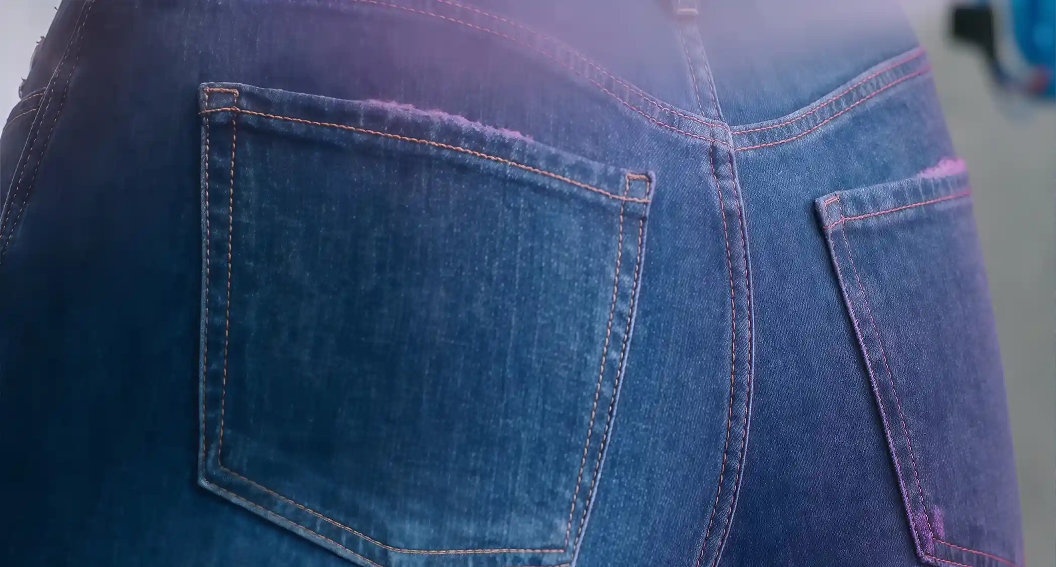 Close-up of denim back pockets showing the color created by automated spraying