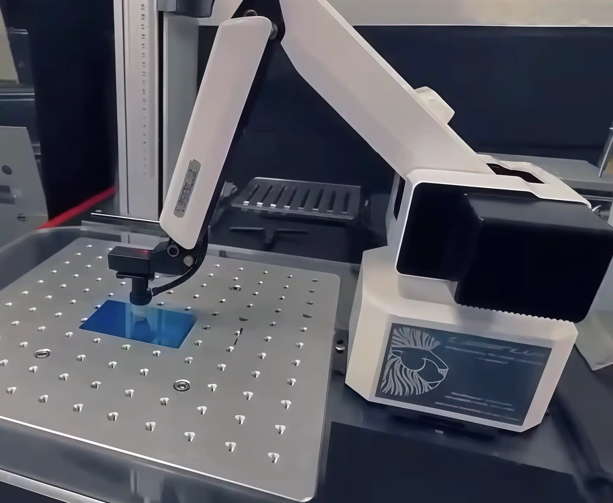 uArm Swift Pro desktop robotic arm placing a workpiece onto a laser engraving machine bed